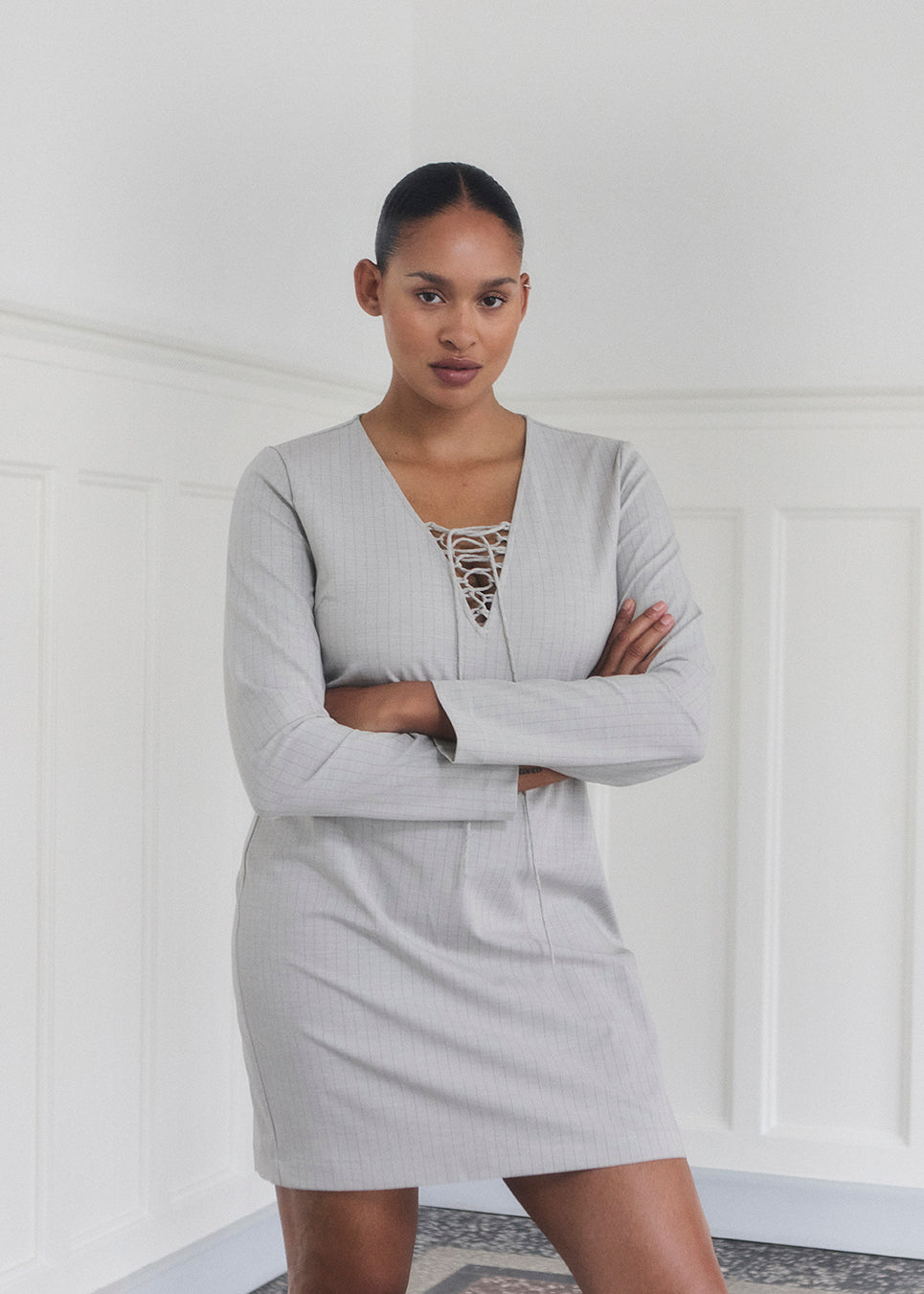 Short fitted dress with a v-neck with a lace-up detail. MickyMD dress has long sleeves and a zipper in the side.