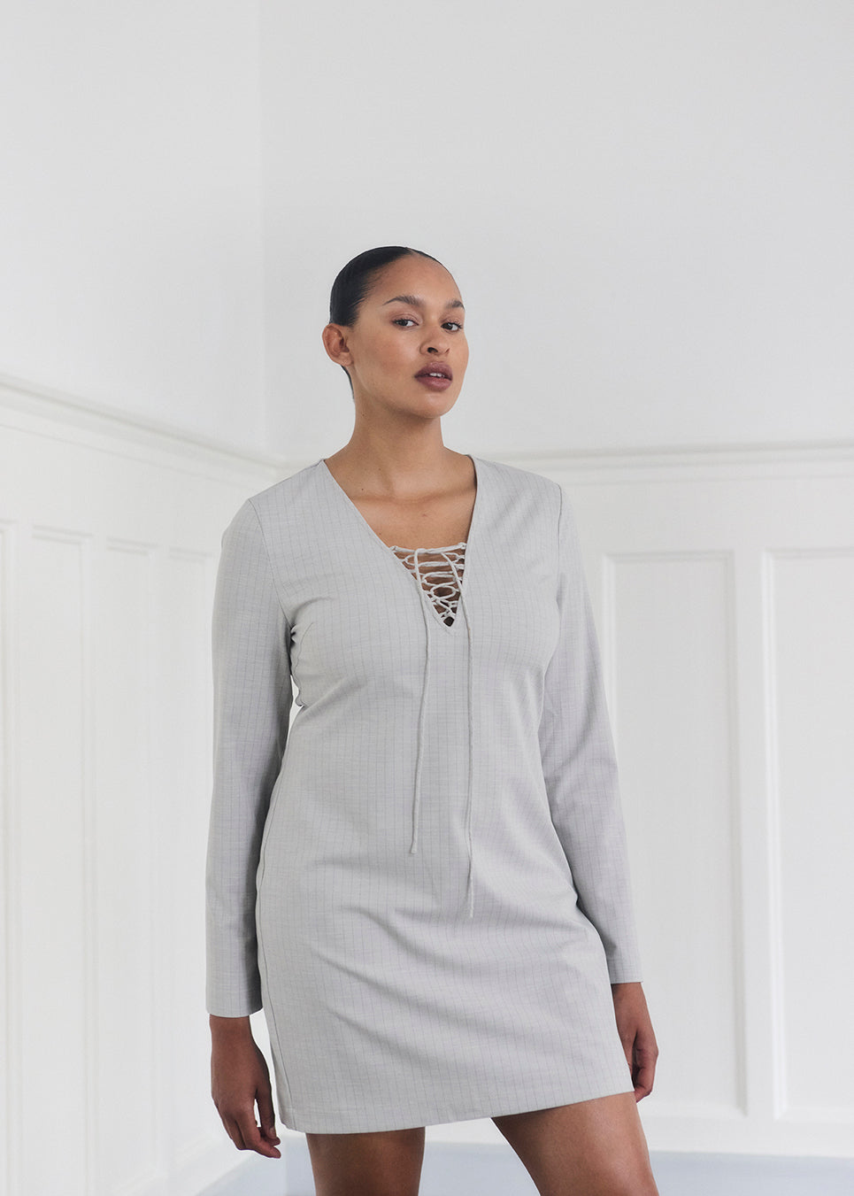 Short fitted dress with a v-neck with a lace-up detail. MickyMD dress has long sleeves and a zipper in the side.