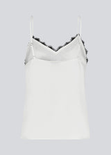 Satin top with a soft drape in white with black lace. TenjaMD top is detailed with lacing on the front and has thin straps.
