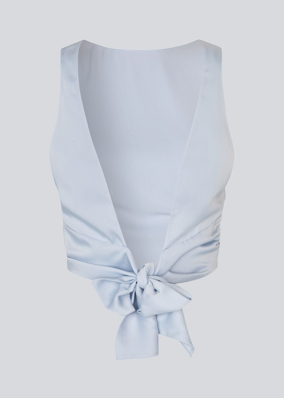The sleeveless top is satin and light gray'ish blue. TailorMD top has an open back with a tieband. The model is 177 cm and wears a size S/36.