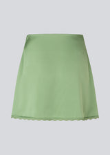 Mini skirt in lustrous satin. The AijaMD Skirt features feminine details such as a lace trim at the hem and a fitted cut that gently flares out at the bottom. The skirt has a discreet side zipper and is made from 100% recycled polyester.