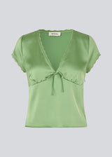 Feminine short-sleeve top in lustrous satin. The AijaMD Top features delicate details such as lace trims, a V-neckline, slight puff under the bust, and a bow detail. Made from 100% recycled polyester, perfect for both elegant and casual looks.