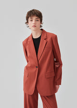 Oversized blazer in the color maple with a drapy fit. AnkerMD blazer has collar and notch lapels with a single button closure. Flap welt front pockets. Slits on cuffs and single back vent. Lined.