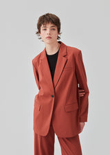 Oversized blazer in the color maple with a drapy fit. AnkerMD blazer has collar and notch lapels with a single button closure. Flap welt front pockets. Slits on cuffs and single back vent. Lined. 