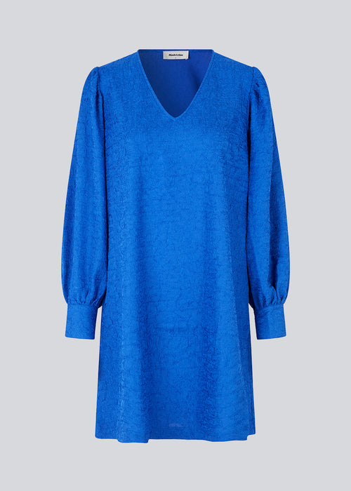 Minidress in blue with long volume sleeves a cuff. BisouMD dress has a v-neckline and an a-shaped silhouette in the body. The model is 176 cm and wears a size S/36