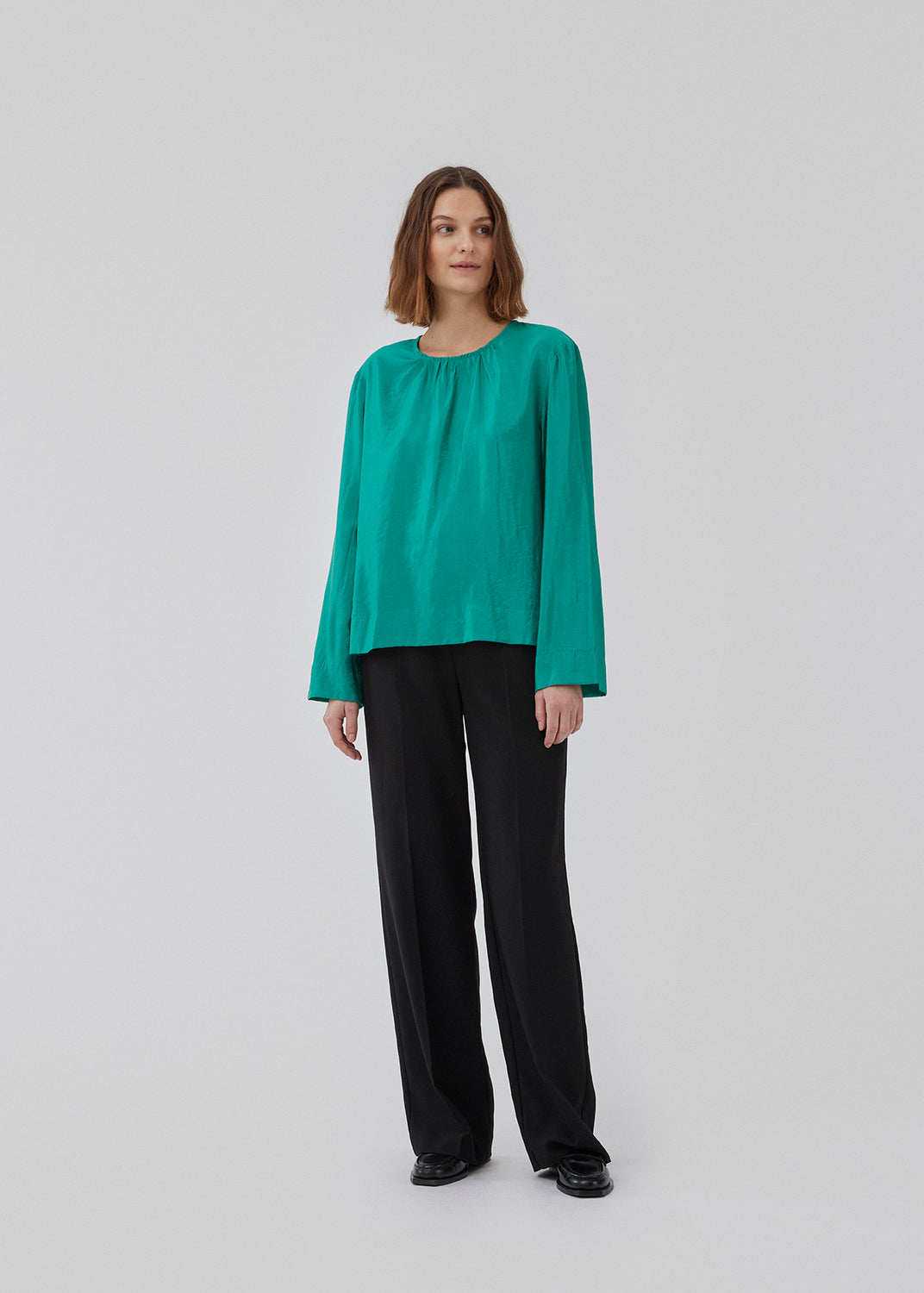 ChristopherMD top in green has a regular body with a round neck with gatherings, and small opening with button closure in the back. Long, wide sleeves. The model is 175 cm and wears a size S/36.