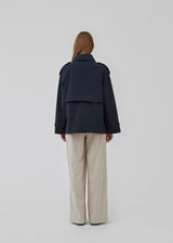 Short trench coat in dar blue in a cotton quality with concealed buttons down the front. Clara jacket has an oversized silhouette and classic details. Lined.