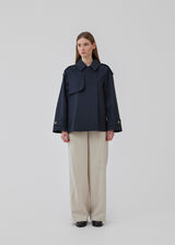 Short trench coat in dar blue in a cotton quality with concealed buttons down the front. Clara jacket has an oversized silhouette and classic details. Lined.