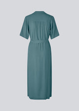 Relaxed shirt dress in blue made from EcoVero viscose. DafneMD long dress has a resort collar, button closure in front, tie belt at the waist, and short sleeves. The model is 177 cm and wears a size S/36.