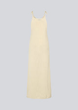 Open knit dress in beige in organic cotton. DariaMD dress has a slim fit with a long skirt, and straps that ties over the shoulder. The model is 177 cm and wears a size S/36.