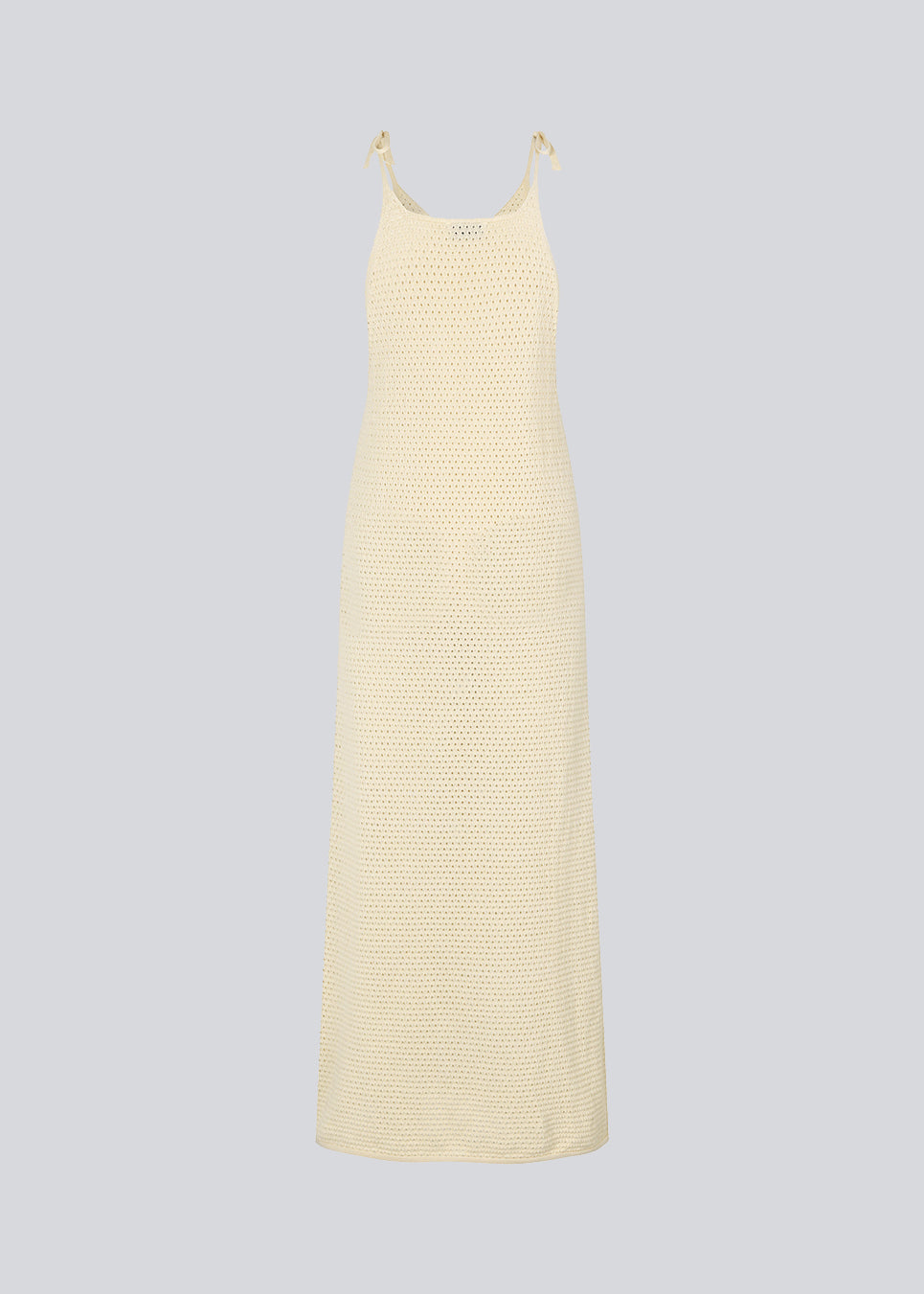 Open knit dress in beige in organic cotton. DariaMD dress has a slim fit with a long skirt, and straps that ties over the shoulder. The model is 177 cm and wears a size S/36.