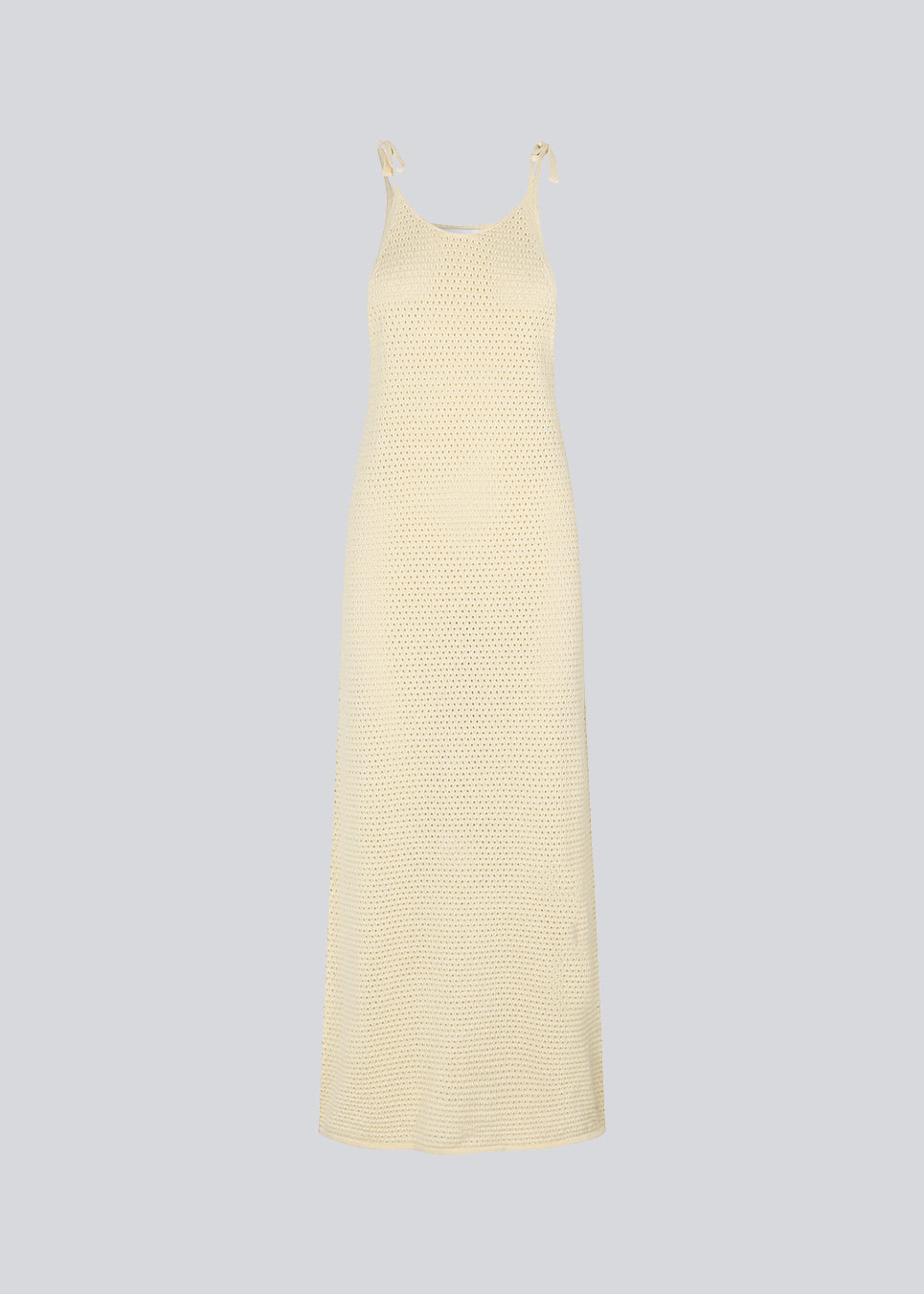 Open knit dress in beige in organic cotton. DariaMD dress has a slim fit with a long skirt, and straps that ties over the shoulder. The model is 177 cm and wears a size S/36.