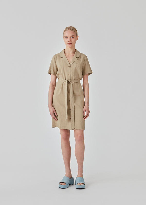 Relaxed shirt dress in beige cut from a linen blend. DarrelMD dress has a resort collar, short sleeves, buttons in front, and a wide tiebelt at the waist. The model is 177 cm and wears a size S/36.