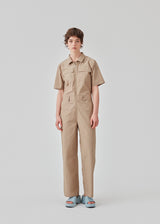 Jumpsuit in a crispy cotton blend with long, wide legs. DedeMD jumpsuit has short sleeves, collar, and zipper down the front. Belt straps at the waist. The model is 177 cm and wears a size S/36.