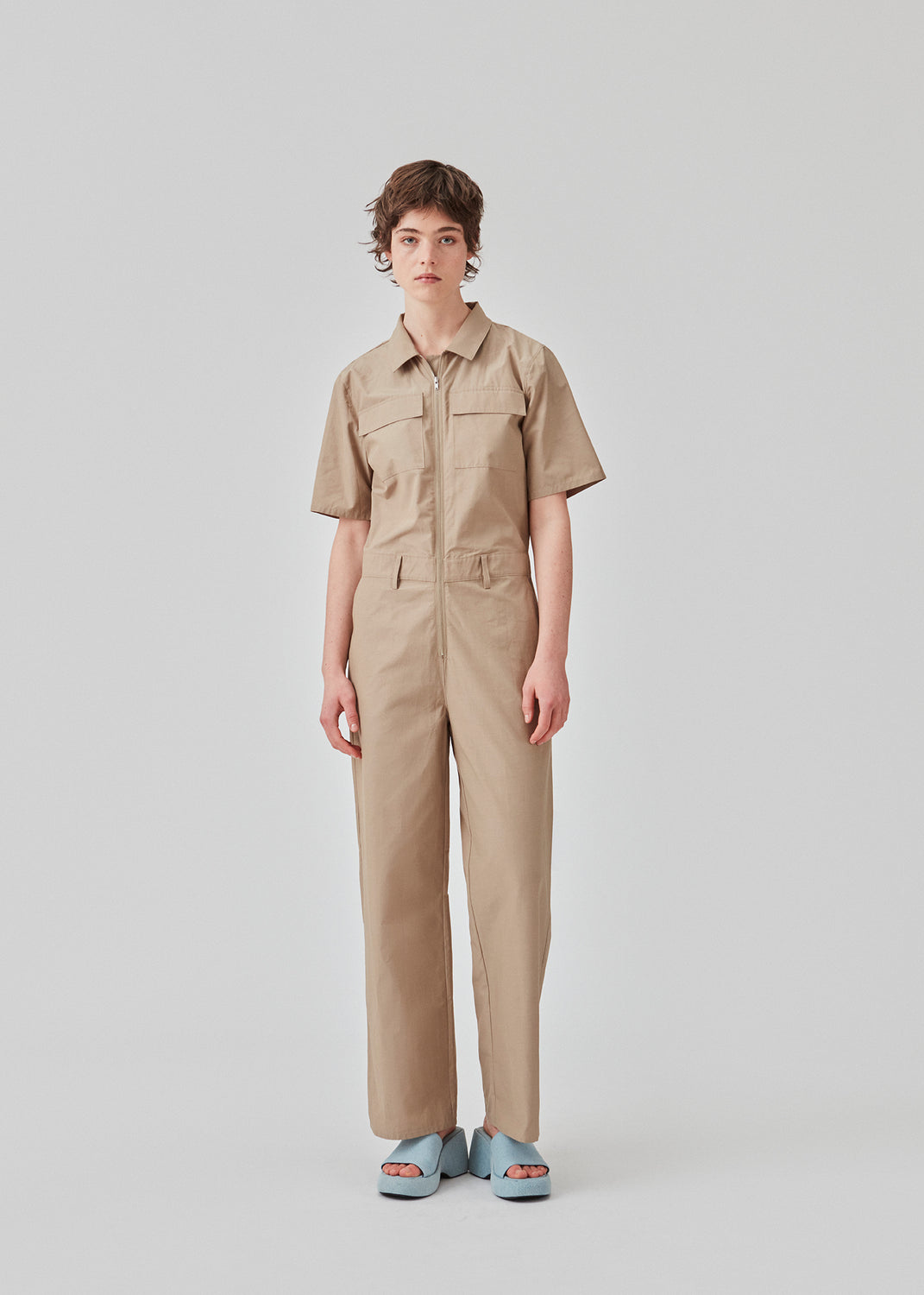Jumpsuit in a crispy cotton blend with long, wide legs. DedeMD jumpsuit has short sleeves, collar, and zipper down the front. Belt straps at the waist. The model is 177 cm and wears a size S/36.