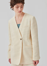 DimeMD blazer is designed in a textured cotton blend with lining. The blazer is collarless but has an asymmetrical wrap detail with a single visible button. The model is 177 cm and wears a size S/36. Style the blazer with matching shorts: DimeMD shorts.