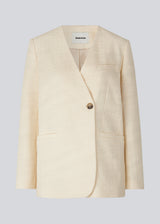 DimeMD blazer is designed in a textured cotton blend with lining. The blazer is collarless but has an asymmetrical wrap detail with a single visible button. The model is 177 cm and wears a size S/36. Style the blazer with matching shorts: DimeMD shorts.