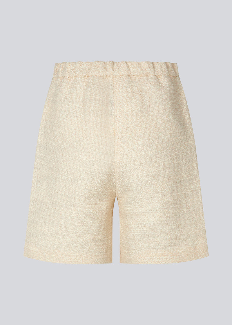Shorts in a textured cotton blend. DimeMD shorts have wide legs cutting mid-thigh, an elasticated waist in the back, and zip fly and button closure in front. The model is 177 cm and wears a size S/36.  Styles shorts with matching blazer: DImeMD blazer.