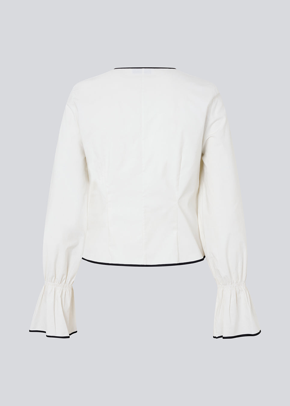 Fitted top in white with long loose sleeves. EmiliaMD shirt is closed with tree black tie bands in front and has a ruffle detail at the sleeve.