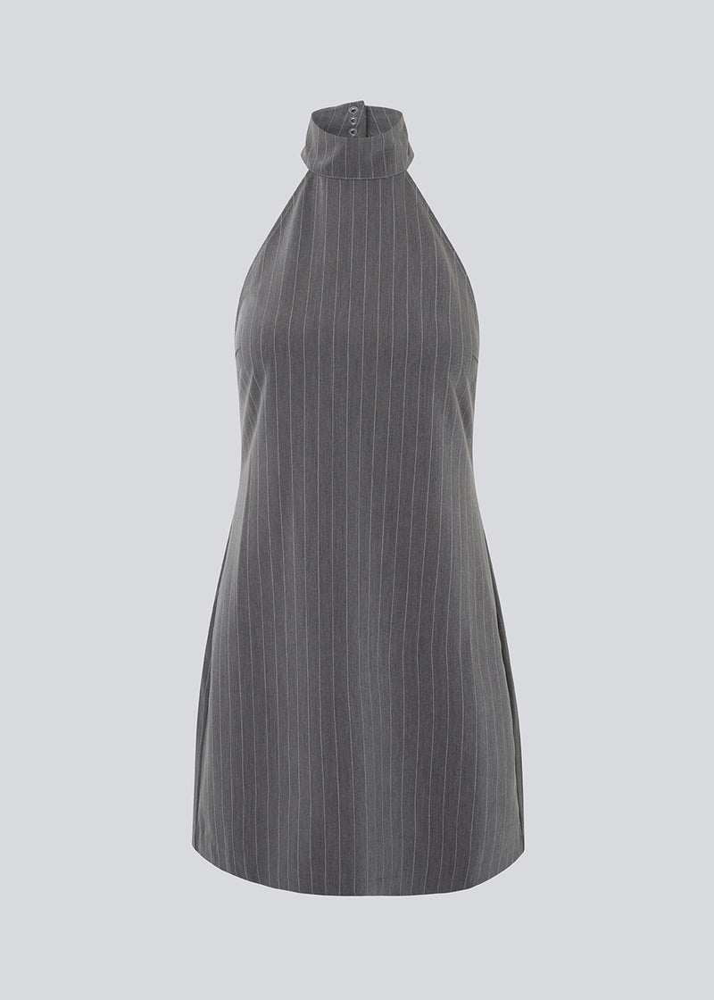 Short fitted dress in grey pinstripe with a halterneck. EmiliaMD halterneck dress has a button closure at the neck and an invisible zipper at the back.