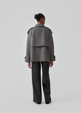 Cropped double-breasted wool coat with hidden buttons. EsmundMD jacket, in the colot Dark Grey Melange, has classic coat details with raglan sleeves and an high yoke at the back. Lined. The model is 175 cm and wears a size S/36.