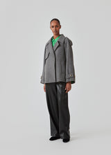 Cropped double-breasted wool coat with hidden buttons. EsmundMD jacket, in the colot Dark Grey Melange, has classic coat details with raglan sleeves and an high yoke at the back. Lined. The model is 175 cm and wears a size S/36.