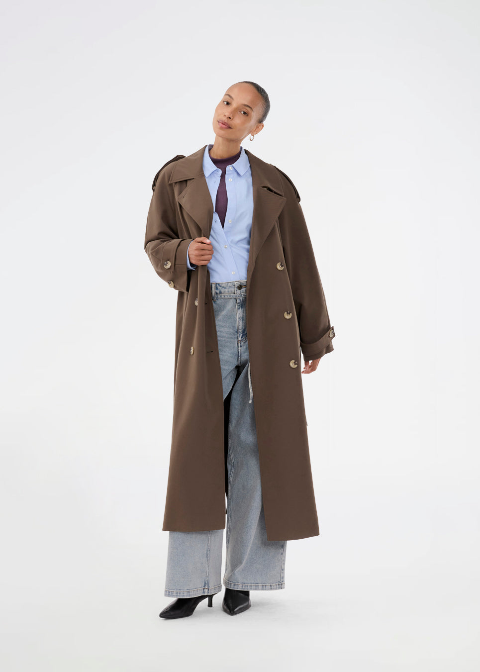 Oversized double-breasted trench coat in dark brown with tie belt at the waist. EvieMD jacket has dropped shoulders and long, wide sleeves. Lined. 