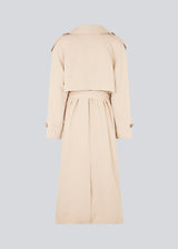 Oversized double-breasted trench coat in light beige with tie belt at the waist. EvieMD jacket has dropped shoulders and long, wide sleeves. Lined. The model is 175 cm and wears a size S/36.
