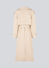 Oversized double-breasted trench coat in light beige with tie belt at the waist. EvieMD jacket has dropped shoulders and long, wide sleeves. Lined. The model is 175 cm and wears a size S/36.
