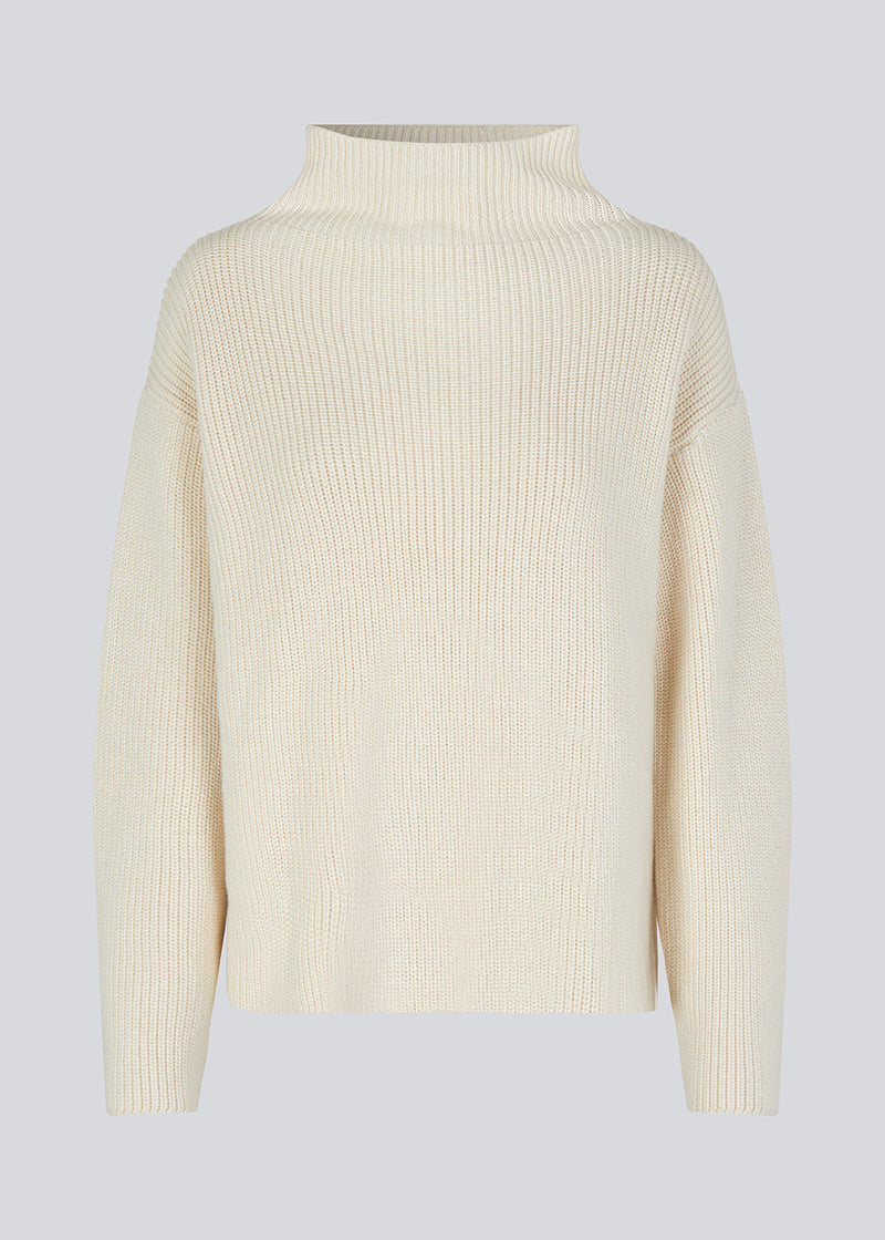 GalenMD t-neck in white knitted from organic cotton with an oversized shape, lange and wide sleeves, along with a high neck and dropped shoulders. The model is 175 cm and wears a size S/36.