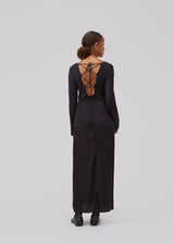 Long sleeved dress in jacquard satin. GraceyMD dress is designed with a relaxed fit and a deep opening in the back with lacing and narrow ties. Slit at center back. The model is 175 cm and wears a size S/36.