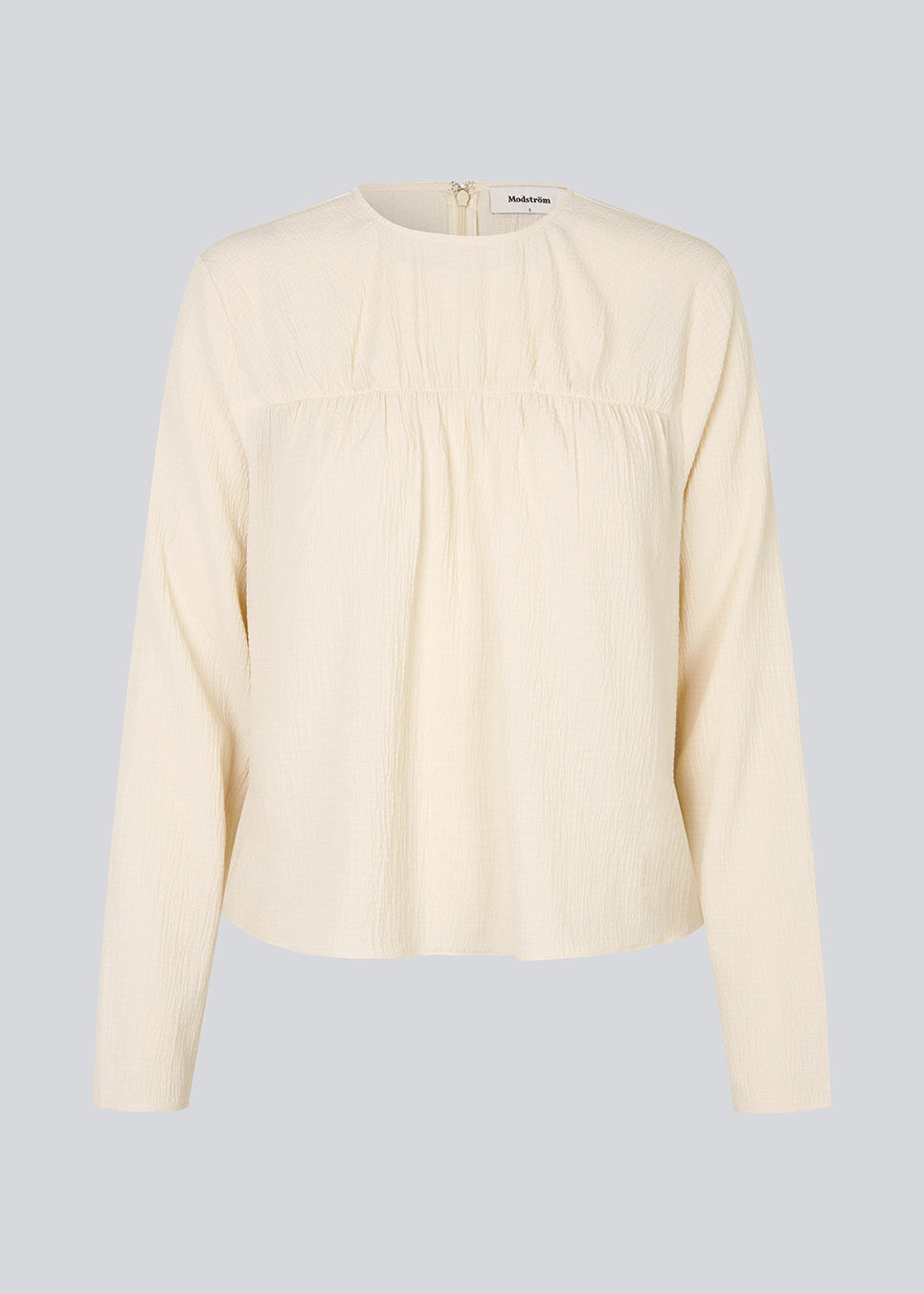 HiltonMD top in beige is designed with a relaxed fit, long sleeves and a round neckline with a hidden zipper at the back. The top is detailed with a ruching detail over the chest. The model is 175 cm and wears a size S/36.