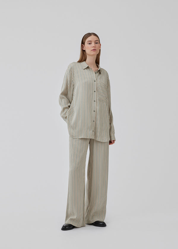 Oversize shirt with collar and button closure in front. HissaMD print shirt has wide sleeves with cuff, and a detailed yoke at the back. The model is 175 cm and wears a size S/36.
