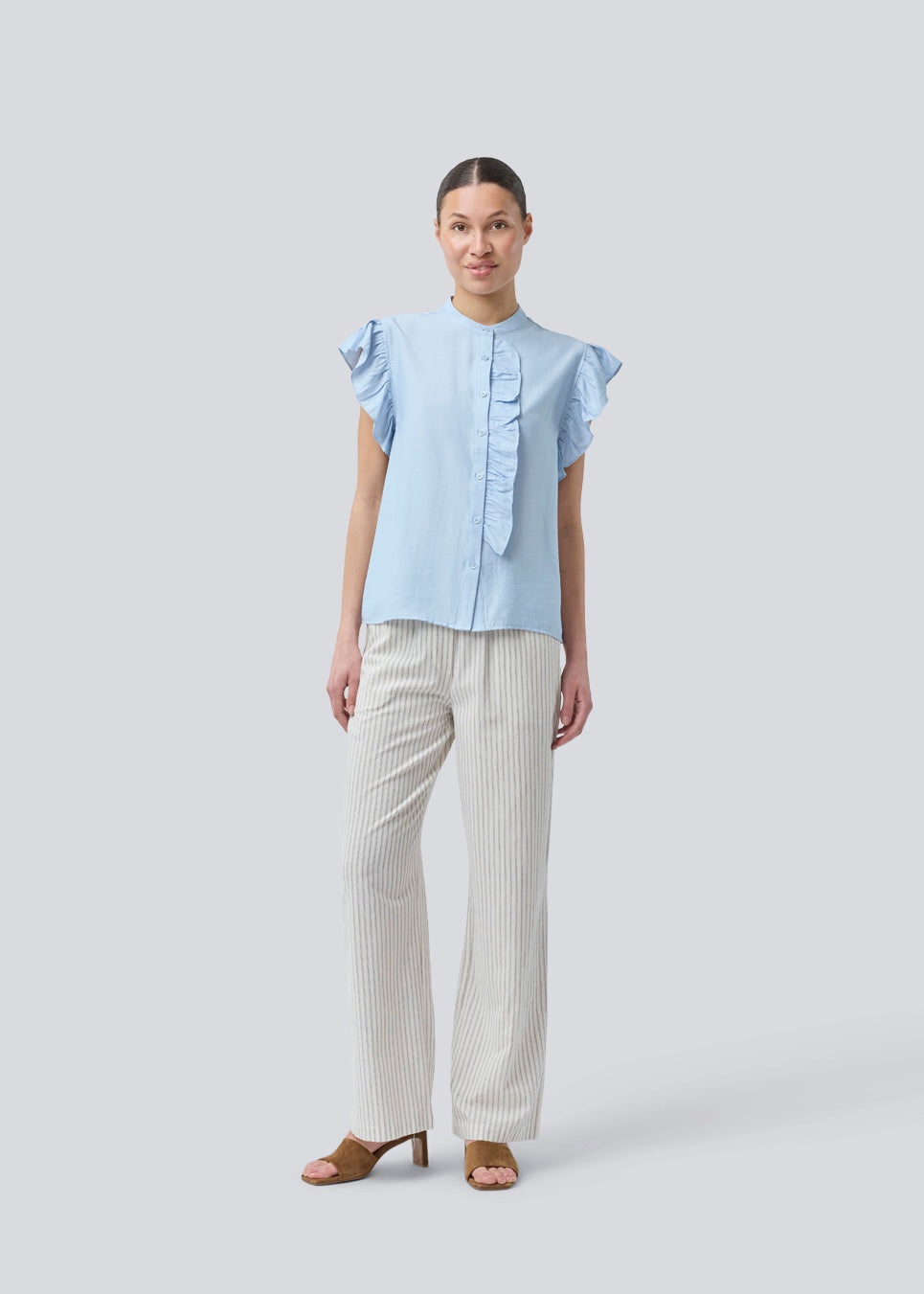 HolidayMD top in light blue is designed with a standing collar and button closure in front. The top has a frilly detail along the placket and at the armholes. The model is 175 cm and wears a size S/36.