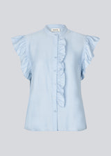 HolidayMD top in light blue is designed with a standing collar and button closure in front. The top has a frilly detail along the placket and at the armholes. The model is 175 cm and wears a size S/36.