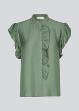 HolidayMD top in soft green is designed with a standing collar and button closure in front. The top has a frilly detail along the placket and at the armholes. 