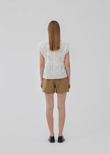 Top in white in broderie anglaise cotton with cutline below the chest with extra volume. HollynMD top has a round neck, short sleeves, and a small opening at the neck with button closure. The model is 175 cm and wears a size S/36.