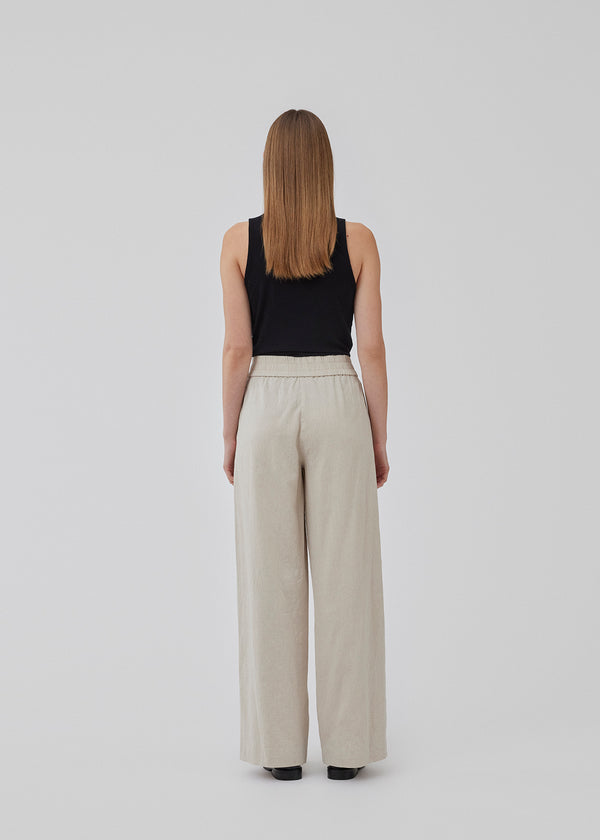 Pants in beige designed with a casual look and fit in a cotton and linen blend. HonorMD pants has loose legs and a medium waist with a wide elastic band. The model is 175 cm and wears a size S/36.