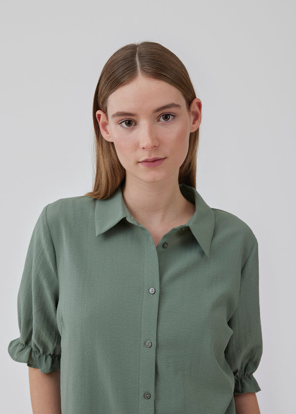 Shirt with a relaxed fit in a recycled material. HuntleyMD shirt has a collar, button closure in front, and short sleeves with ruffles. The model is 175 cm and wears a size S/36.