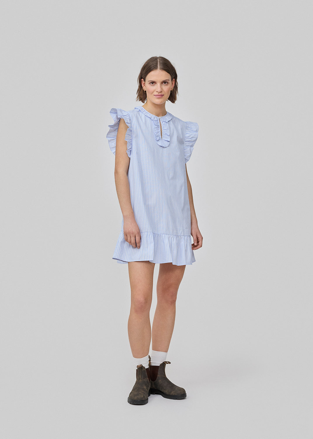 Short, sleeveless dress with ruffle details. The InaraMD dress has an opening in the front with a and button closure and decorative ruffles. The model is 177 cm and wears a size S/36