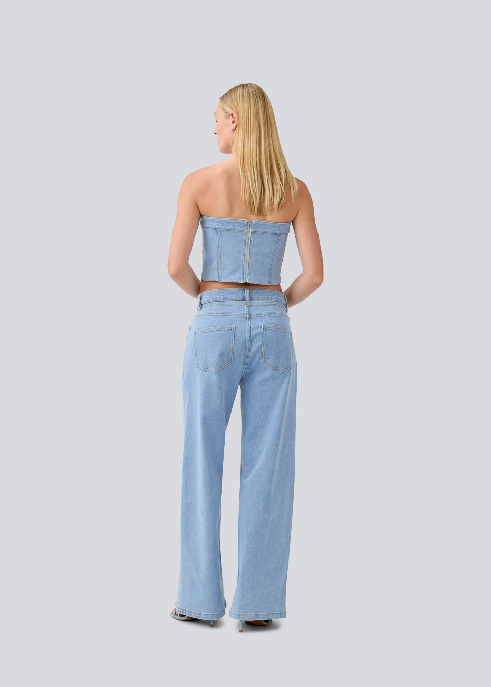 Short denim top in a corset design. IvannaMD top in made in light colored denim and is closed with a zipper at the back.