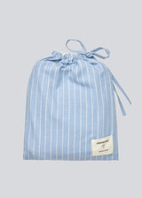 Blue classic striped pyjamas. The pyjamas is sold as a set of shirt and pants in the same size. Josefinemd pyjamas are made from 100% soft cotton and feature a classic fit with a collar, button closure, and drawstring trousers. Finished with delicate wave trim and comes with a matching pouch with logo. Josefine Vogt (165 cm) and the model (177 cm) are both wearing size Small.