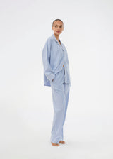 Blue classic striped pyjamas. The pyjamas is sold as a set of shirt and pants in the same size. Josefinemd pyjamas are made from 100% soft cotton and feature a classic fit with a collar, button closure, and drawstring trousers. Finished with delicate wave trim and comes with a matching pouch with logo. Josefine Vogt (165 cm) and the model (177 cm) are both wearing size Small.