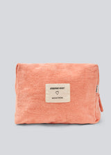 Peach colored toiletry bag with a sewn-on logo. Josefinemd toiletry bag is minimalist and made from organic cotton with a light blue lining and zip closure. Practical and elegant – a must-have for travel or the bathroom.
