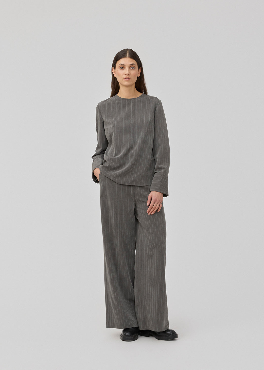 Pants in grey pinstripe with wide legs. KemmaMD pants has side pockets, a medium high waist, zipper and paspoil back pockets.