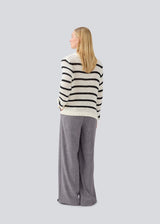 Klassisk strik i hvid med sorte striber i en løs pasform. MaddieMD stripe o-neck har en rund hals og slids i siderne. Modellen er 177 cm og har en str S/36 på.