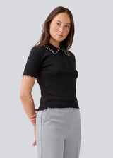Fitted polo in black with white edges in jersey. MagdaloneMD polo has short sleeves and babylock edges. The model is 177 cm and wears a size S/36