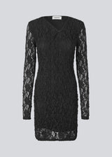 Short fitted dress in an elastic lace material. MalmunMD dress has an asymmetric neckline with an opening with button closure.