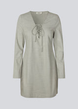 Short fitted dress with a v-neck with a lace-up detail. MickyMD dress has long sleeves and a zipper in the side.