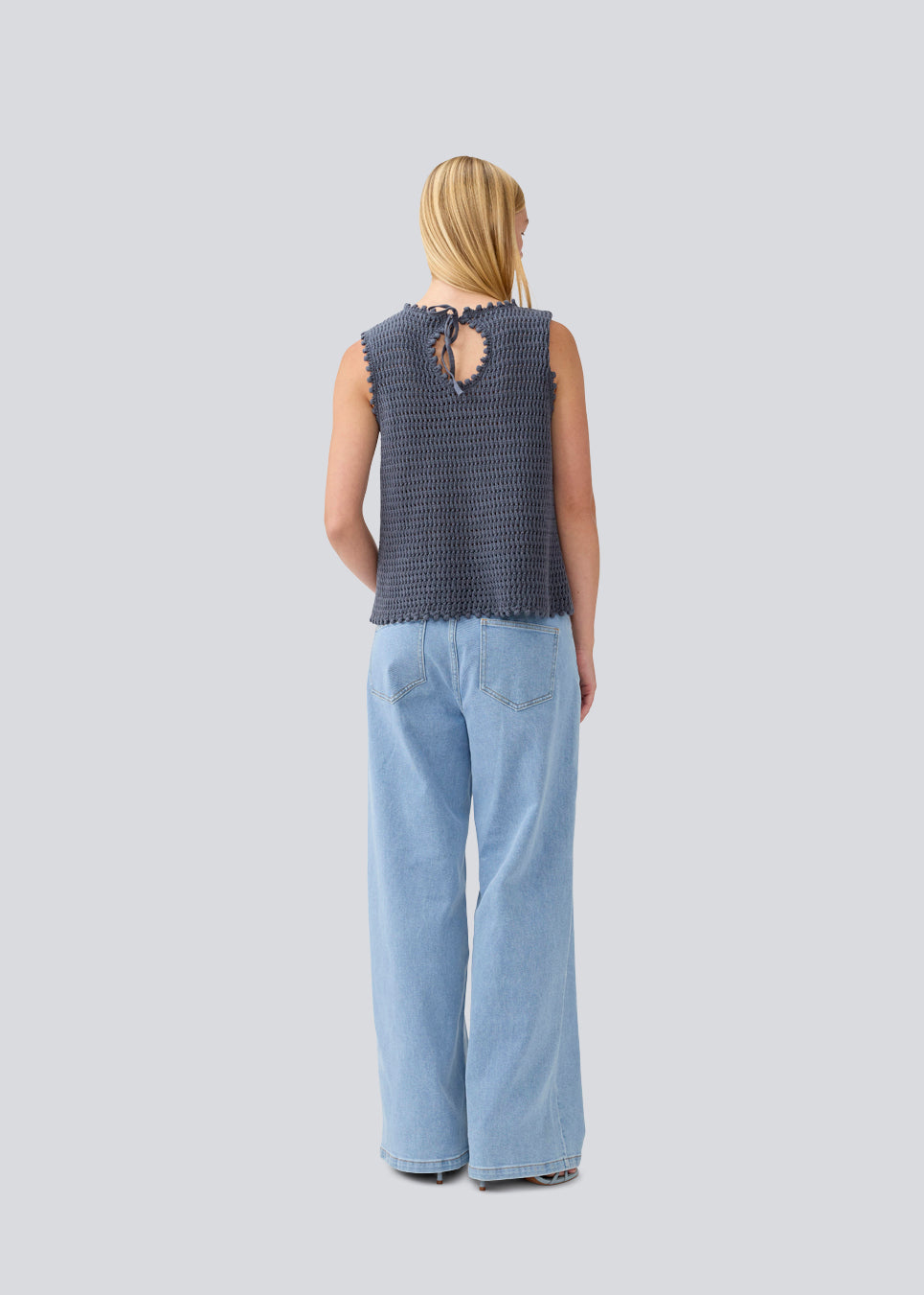 Crochet top in blue without sleeves in organic cotton. MieMD top has detailed trimmings and a deep v-neckline in the back with a tieband closure. The model is 177 cm and wears a size S/36.